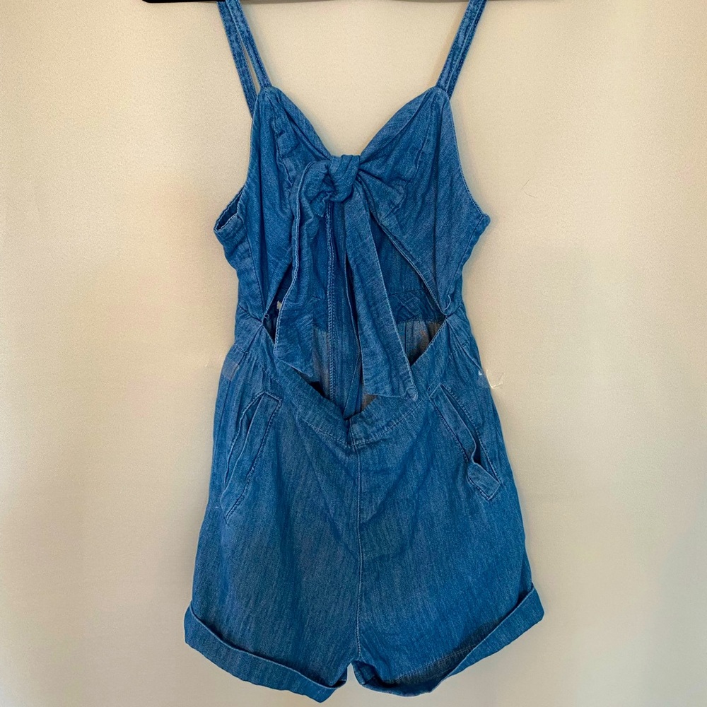 Denim romper with adjustable straps and tied bow in front